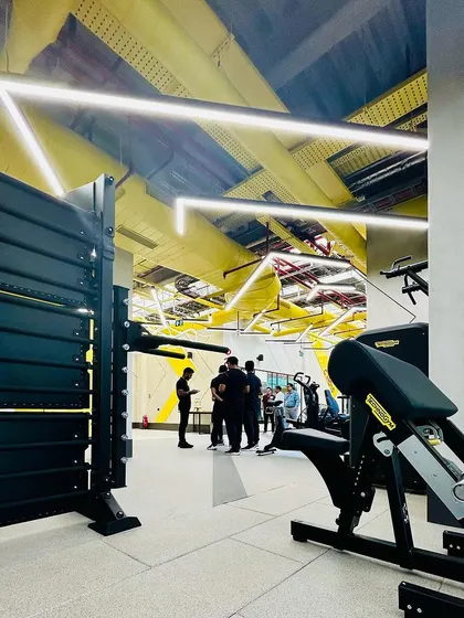 A view of the strength training equipment at the DLF Thrive Chennai gym. The layout is spacious and organized, with angular lighting overhead guiding the flow and enhancing the energetic atmosphere.