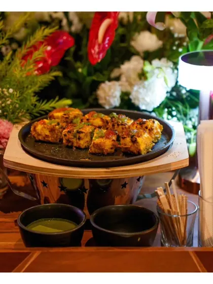A platter of sizzling Paneer Tikka, served on a mini sizzler plate to keep it warm and add a touch of tableside drama.
