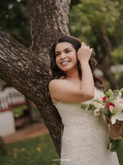 A candid and happy portrait of the bride, leaning against a tree and smiling.