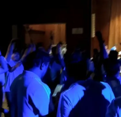The crowd with hands up, dancing to regional hits at a corporate party.