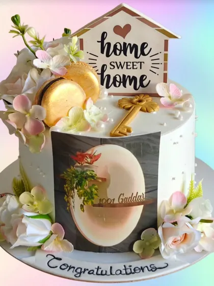 A lovely cake to celebrate a new beginning in a new home. This housewarming cake is decorated with fresh flowers, macarons, and a "Home Sweet Home" topper.