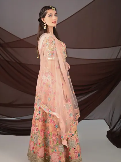 An international model showcases a beautiful peach floral lehenga. The delicate embroidery and soft colors are perfect for a daytime event.