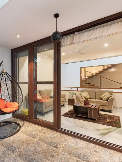 The patio of the Twin Courtyard House, featuring patterned tiles and a comfortable swing chair. This space acts as a perfect transition between the interior living area and the garden.