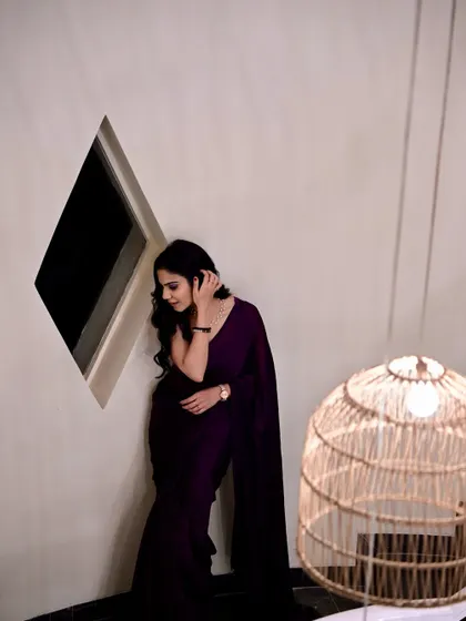 A candid, thoughtful pose in the same purple saree, showing a different mood and expression.