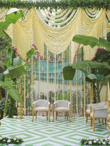 A unique South Indian inspired decor with a geometric-patterned floor, banana plants, and a curtain of jasmine flowers.