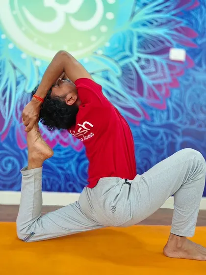 A deep expression of the One-Legged King Pigeon Pose, with the foot touching the head, showing advanced spinal flexibility.