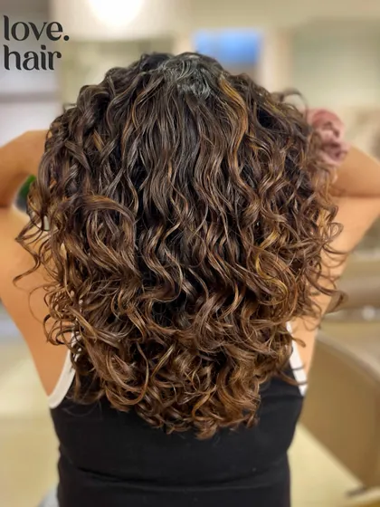 The back view of these lush, colored curls. The cut is designed to give the hair shape and volume, preventing it from looking weighed down.