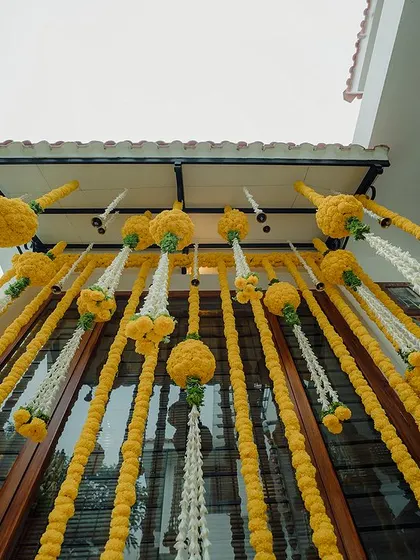 An upward view of the stunning Haldi backdrop, with marigold balls and tuberose streamers creating a picture-perfect setting.