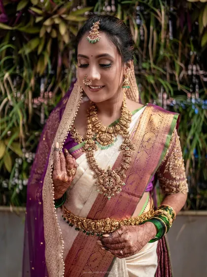 A detailed portrait focusing on the bride's magnificent jewelry and the rich textures of her saree. Her gentle smile reflects the happiness of her special day.