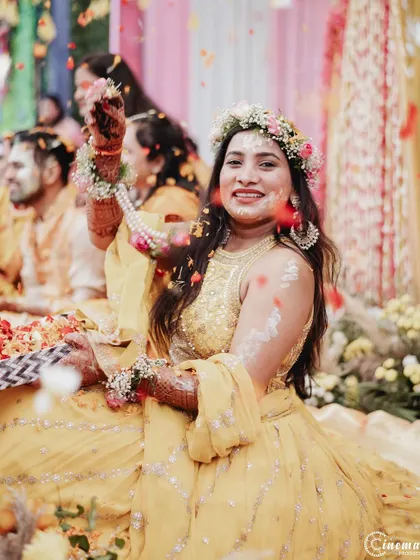 A beautiful portrait of the bride during her Haldi, with flower petals frozen in mid-air, creating a magical effect.