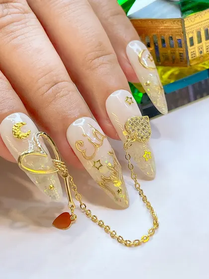 Another view of the stunning Eid nail art, focusing on the delicate gold charms and the shimmering base.