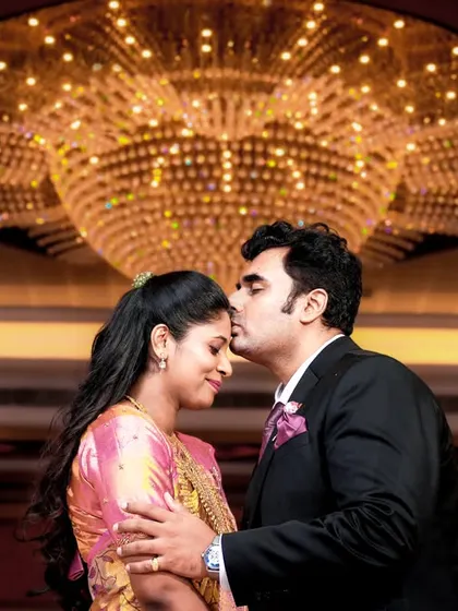 A tender forehead kiss under a magnificent crystal chandelier, creating a glamorous and romantic atmosphere.