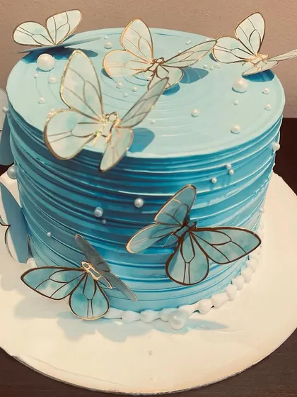 A vibrant blue butterfly cake. The textured frosting and gold-trimmed butterflies create a beautiful and eye-catching design.