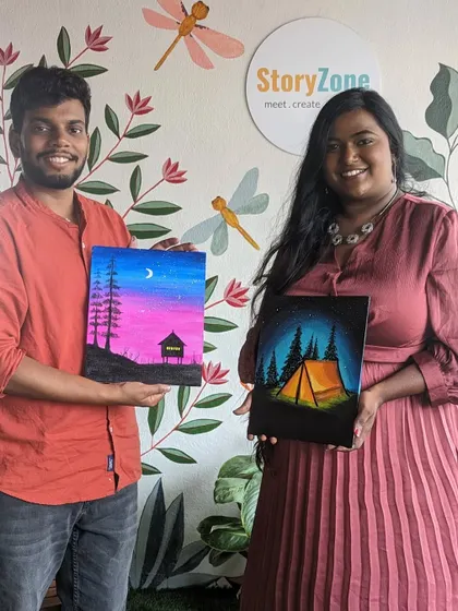 A couple proudly displaying their finished nightscape canvas paintings. A great date idea!