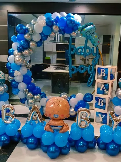 A "Baby Boy" welcome home decoration with multiple balloon pillars, 'BABY' foil letters, and an arch.