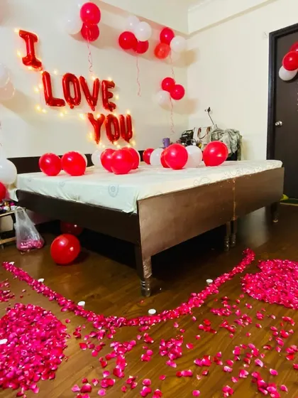 A full view of the romantic room setup, with a heart shape made of rose petals on the floor in front of the bed.