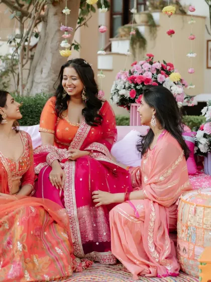 The bride chatting with her bridesmaids at the Mehendi, all dressed in beautiful, coordinated outfits.