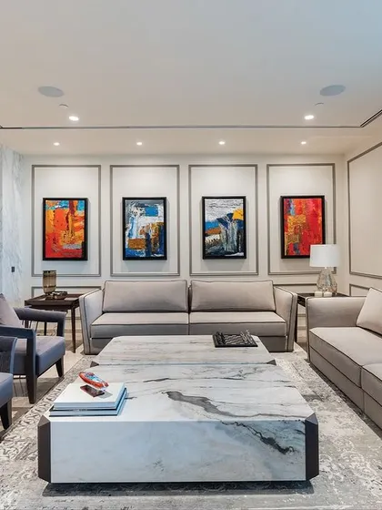 This living room uses a cool, neutral palette of grays and whites. Our custom sofas and armchairs with unique metal-frame details are paired with a substantial marble coffee table, creating a sophisticated and modern space.