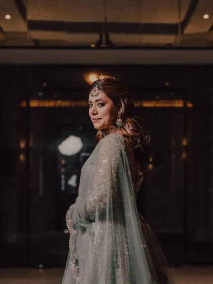 A graceful over-the-shoulder portrait of the bride, her expression confident and happy, ready to celebrate her cocktail night.