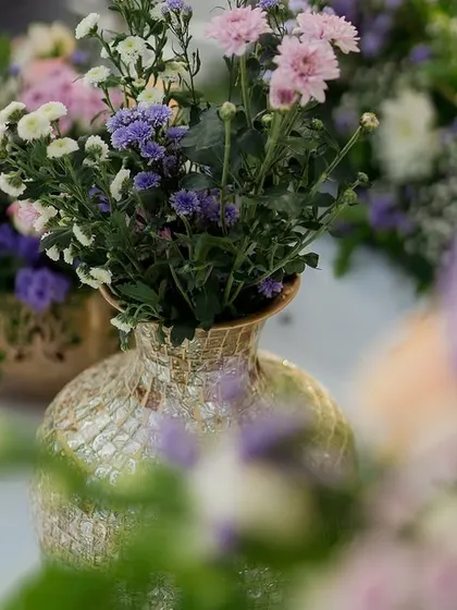A close-up of the pastel floral arrangements used in our Chamundi Hills engagement setup, featuring soft purples and pinks in elegant golden vases.
