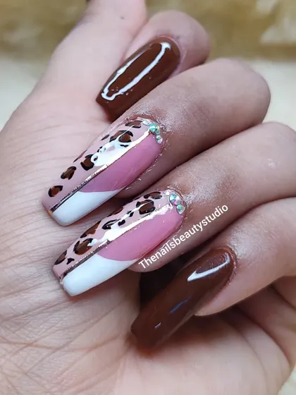 This bold design combines a classic white French tip with hand-painted leopard print and a solid chocolate brown polish for a trendy look.