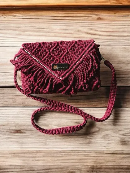 A full view of the maroon fringed clutch, showing off its beautiful strap and detailed knotwork.