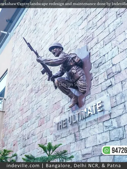 A powerful bronze sculpture of a soldier, "The Ultimate," mounted on a stone wall at Manekshaw Centre. I ensure the surrounding landscape complements such important features.