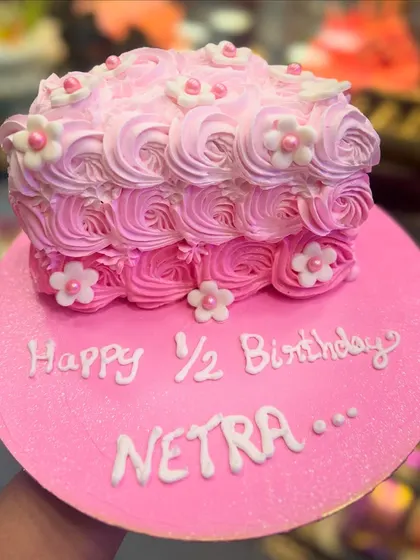 A half-birthday cake with pink ombre rosette piping. This design is elegant and sweet, perfect for celebrating the six-month milestone for a baby girl.