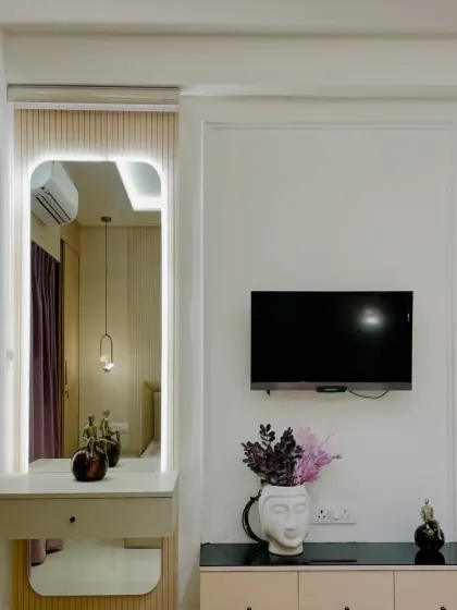 This bedroom includes a compact and stylish vanity area with an illuminated mirror. It's a perfect example of how we integrate functional spaces beautifully.