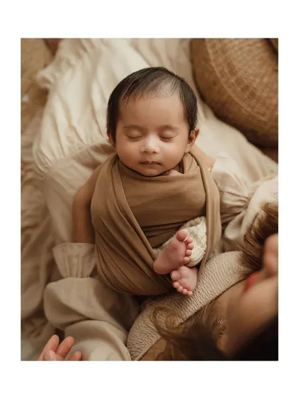 A close-up of a newborn's tiny feet peeking out from their swaddle.