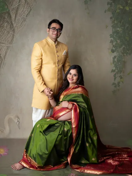 A classic portrait of the expecting couple. The dad-to-be, in a handsome yellow kurta, stands proudly with his wife in her beautiful green and red saree.
