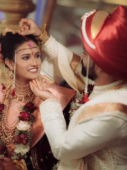 A beautiful, candid moment as the groom applies the bindi. The bride's joyful smile makes this a heartwarming and memorable shot.