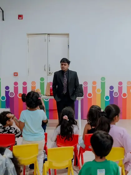 Standing before a seated audience of children at a colorful event space. I command the stage and ensure that even the kids in the back row are fully engaged.