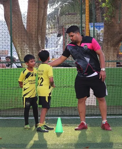 A coach gives one-on-one feedback to two young players. This personalized attention is a cornerstone of my coaching philosophy.