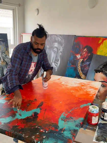 A different angle of me working in the studio. You can see other completed and in-progress works in the background, giving a sense of the creative environment.