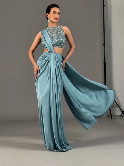A full-length shot of a modern draped saree. The clean updo and fresh makeup complete this chic and fashion-forward look, ideal for a cocktail event or reception.