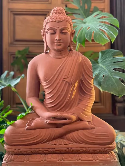This red sandstone Buddha in meditation pose exudes boundless light and stillness, making it a divine addition to a quiet garden corner.