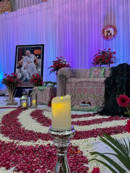 This perspective shows the pathway of devotion we created with flower petals, leading towards the decorated stage. The soft glow from the electric candle adds to the tranquil mood of the satsang.