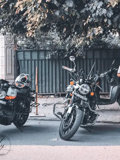 An atmospheric shot of two Royal Enfield motorcycles parked under a tree. This image focuses on the bikes themselves, capturing the aesthetic and mood of a rider's break during a journey.