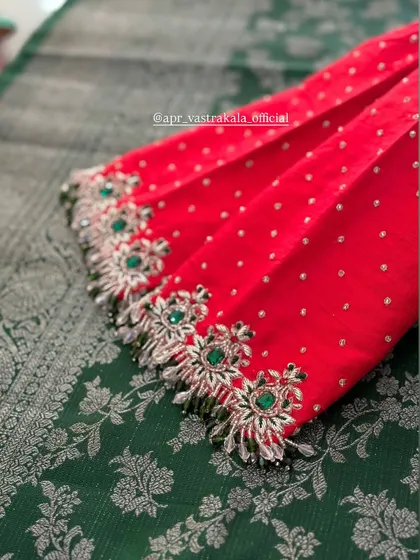 A red blouse with silver and green floral embroidery on the sleeve cuffs.