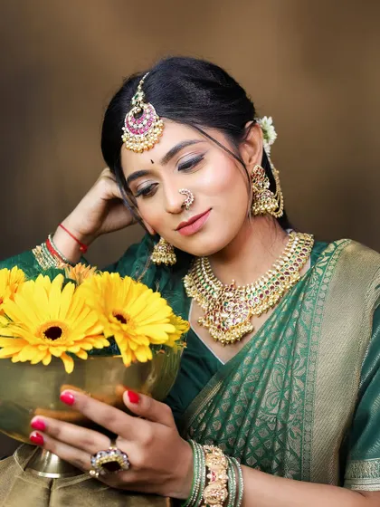 The model's serene expression captures the festive spirit. The jewellery, including the choker, jhumkas, and nose ring, are all available for rent.
