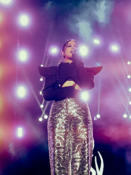 A full-length shot of Agsyworld, highlighting her stage presence and outfit against a backdrop of brilliant lights. Capturing the artist's complete look is key for performance photography.