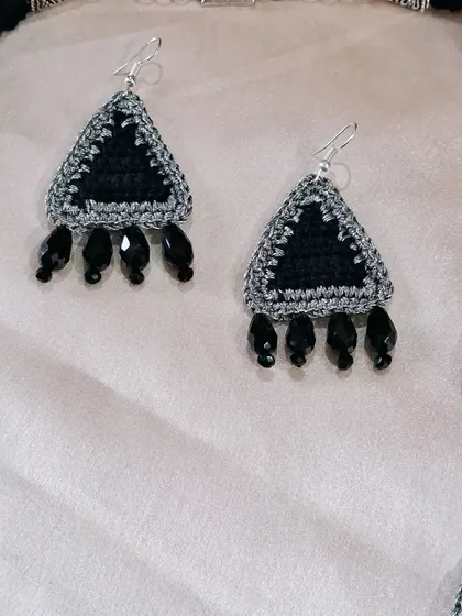 A close-up of the triangular crochet earrings, part of a custom set. The black beads add a touch of elegance and tie the design together with the matching necklace.