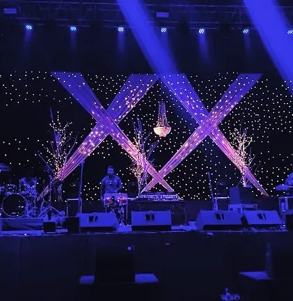 The same sangeet stage viewed with dramatic blue stage lighting, showing how the atmosphere can be transformed for performances.