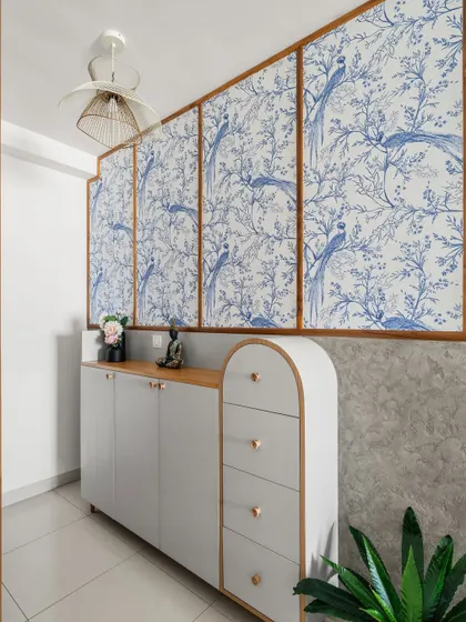 A well-thought-out foyer can make a living room feel more expansive. Here, we used light-toned furniture, curved details, and a beautiful blue and white wallpaper to create a light and airy entrance.