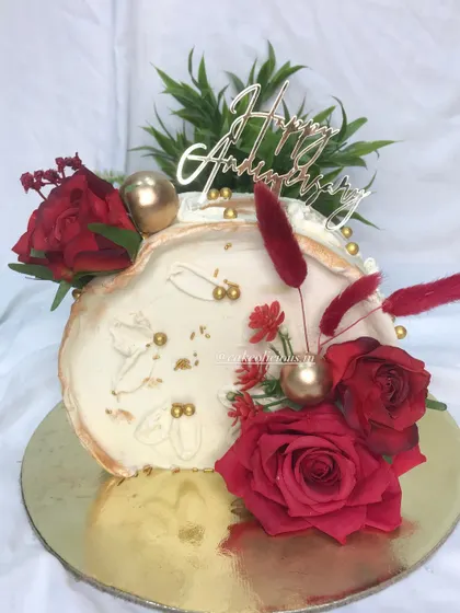 A top-forward cake designed for an anniversary. The combination of red, white, and gold is timeless. This chocolate mousse cake is finished with white ganache, a fault line design, and decorated with rich red roses.