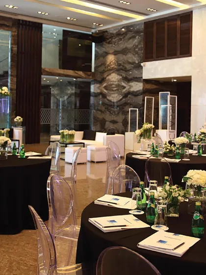 A banquet setup for a corporate dinner, featuring round tables with black linens and ghost chairs. This modern and sophisticated arrangement is perfect for networking events, award ceremonies, or gala dinners.