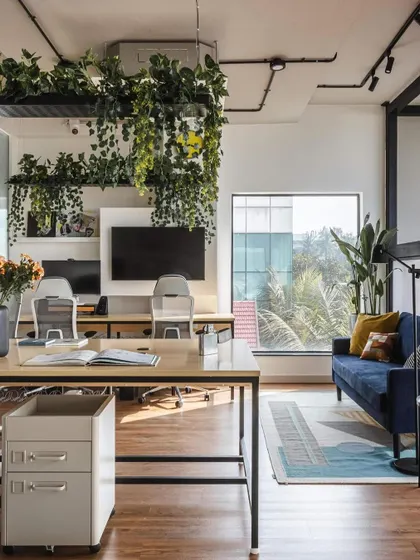 This view highlights the founder's cabin, which includes a small lounge area for informal meetings. The design uses suspended gardens to create a natural, calming canopy over the workspace.