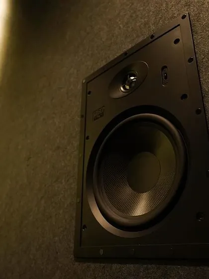 A detailed shot of an OSD Black T83 surround speaker, which provides clear and immersive audio. The in-wall installation keeps the focus on the room's design.