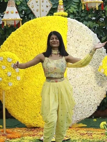 Posing in front of a magnificent floral backdrop at a Haldi ceremony. The vibrant yellow and white flowers perfectly captured the joyful spirit of the event.